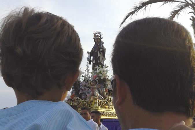 Un padre y su hijo contemplan la procesión del Carmen de Benajarafe